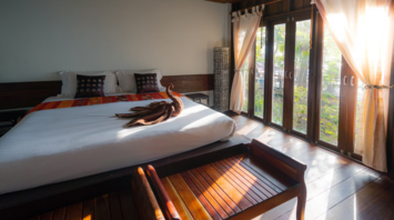 Modern hotel room with wooden interior and sunlight streaming through large windows