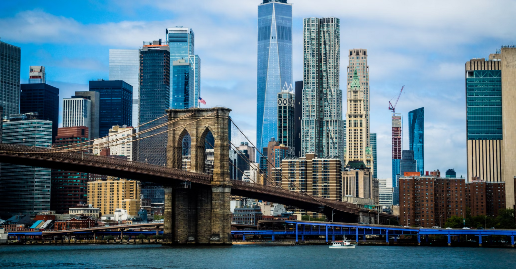 Brooklyn Bridge with Manhattan skyline in the background on a partly cloudy day