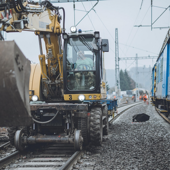 Construction vehicle working on railway tracks near passenger trains