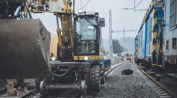 Construction vehicle working on railway tracks near passenger trains