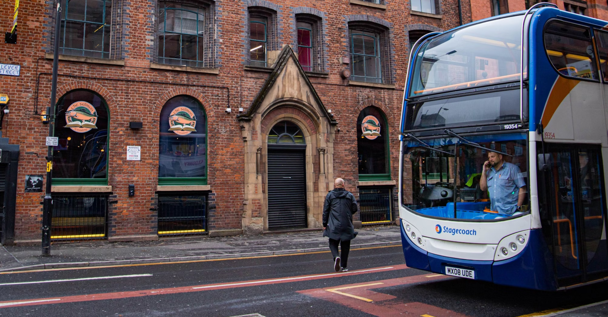 People near a double-decker Stagecoach bus on a city street with brick buildings