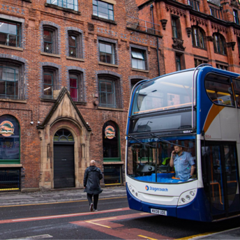 People near a double-decker Stagecoach bus on a city street with brick buildings