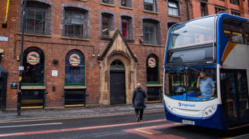 People near a double-decker Stagecoach bus on a city street with brick buildings