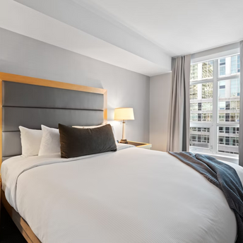 Hotel room with a large bed, two lamps, and window curtains