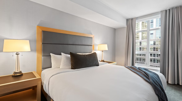 Hotel room with a large bed, two lamps, and window curtains