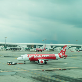 AirAsia aircraft being towed at an airport gate on a cloudy day