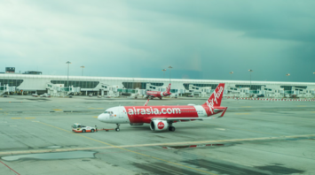AirAsia aircraft being towed at an airport gate on a cloudy day