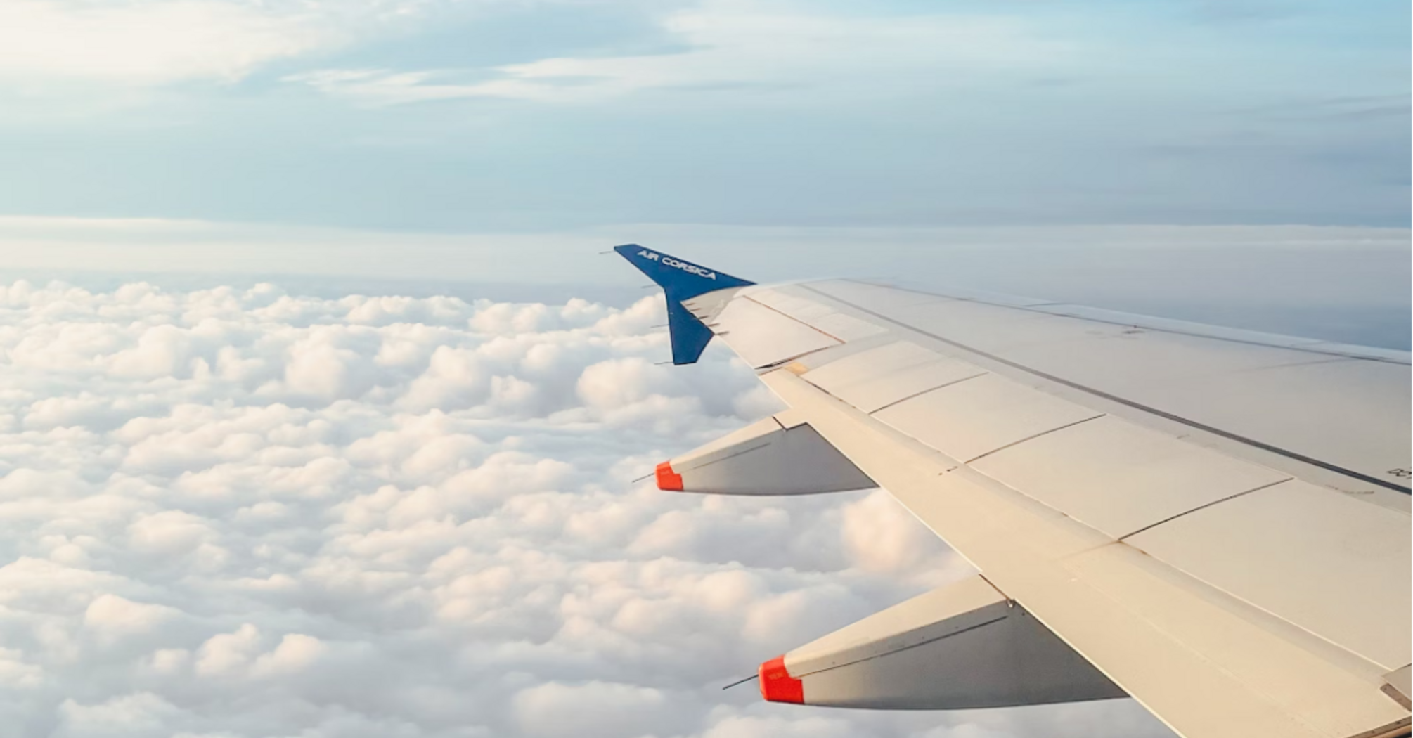 Air Corsica aircraft wing above the clouds during flight