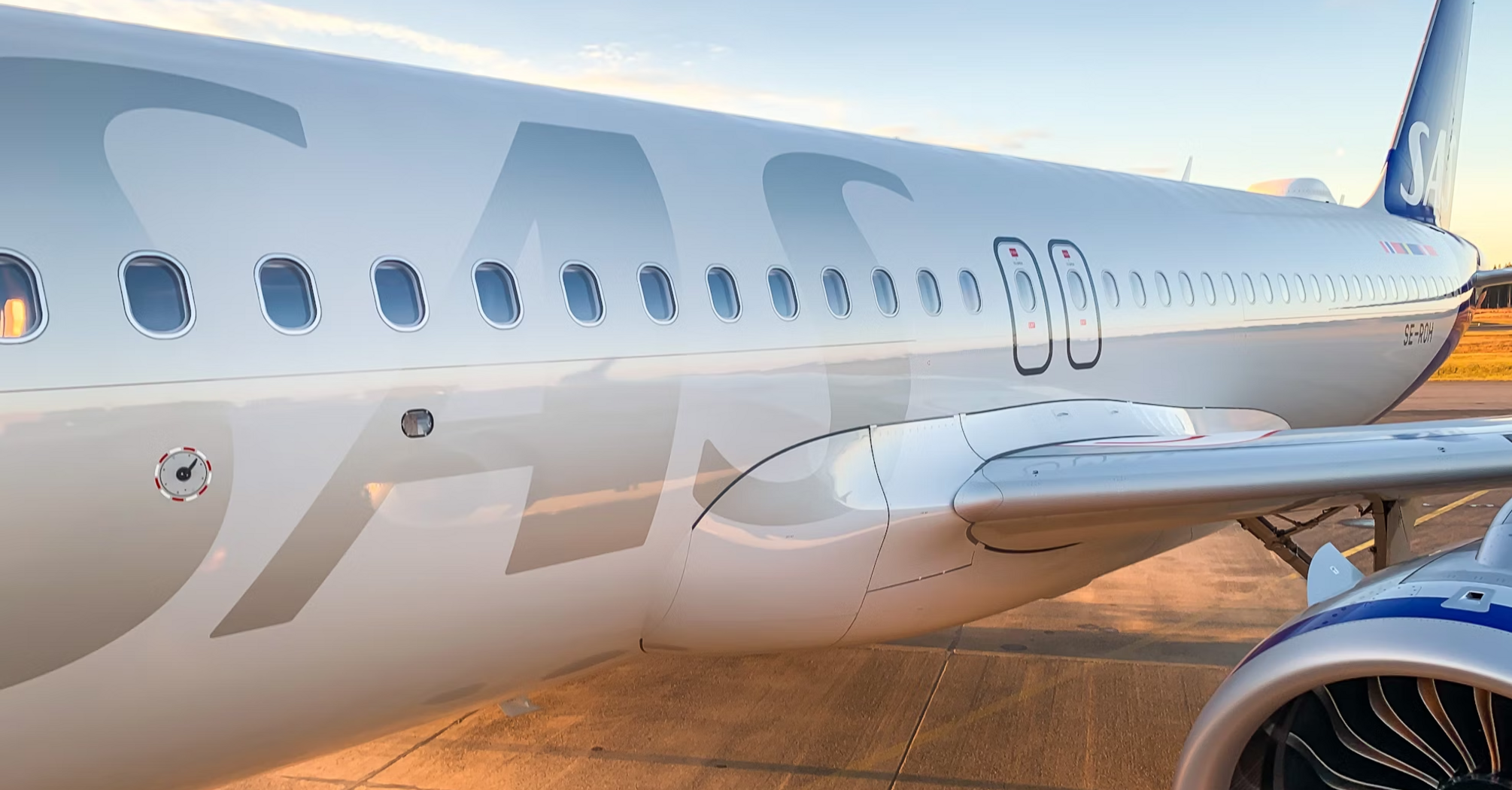 Close-up of a Scandinavian Airlines aircraft parked on the tarmac at sunset
