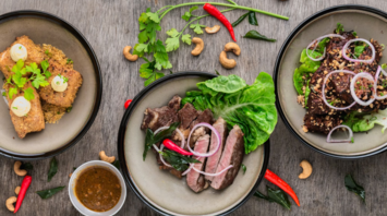 Three diverse dishes served in food hall style with herbs and spices