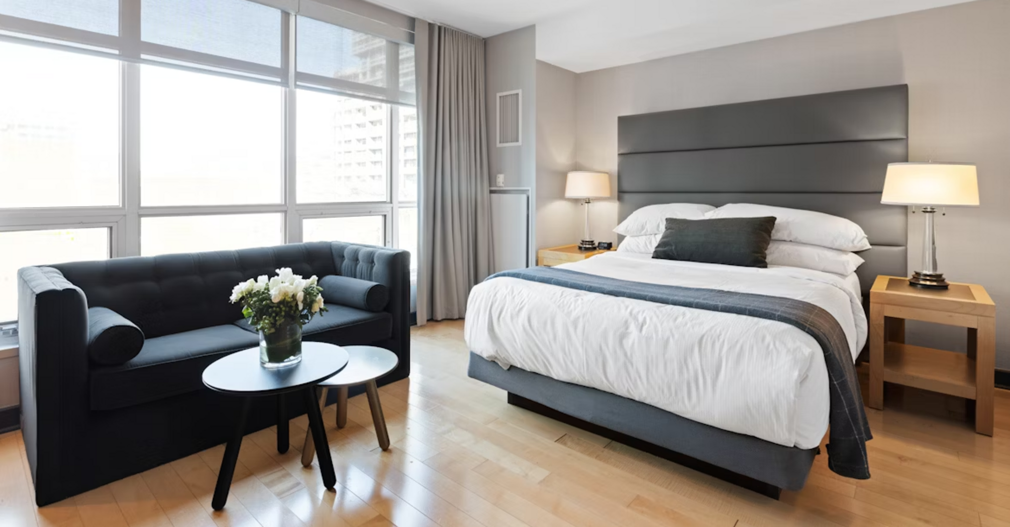 Modern hotel room with bed, sofa, and large windows