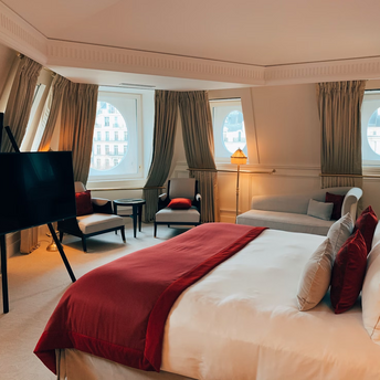 Luxury hotel suite with round windows, red bedding, and city view