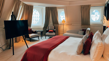 Luxury hotel suite with round windows, red bedding, and city view