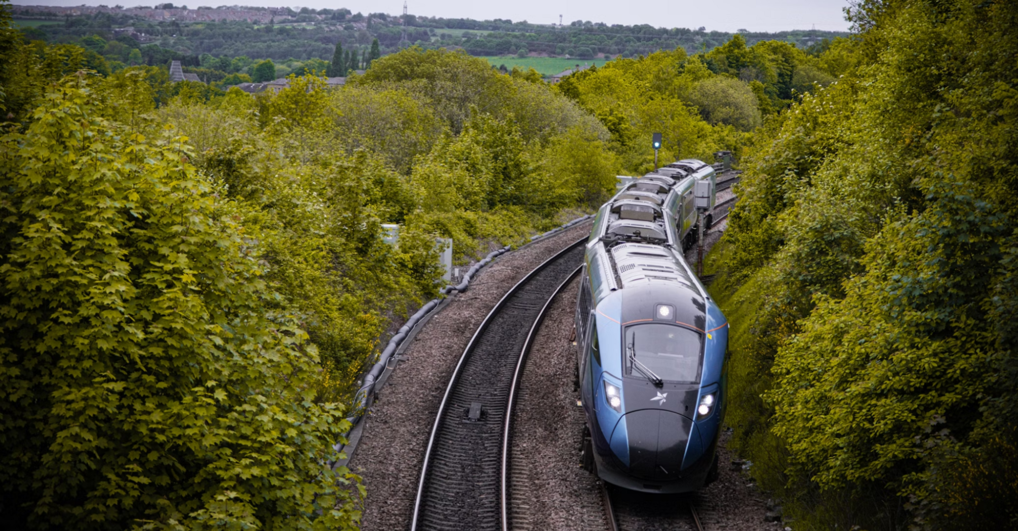 Modern passenger train traveling through lush green countryside in Northern UK