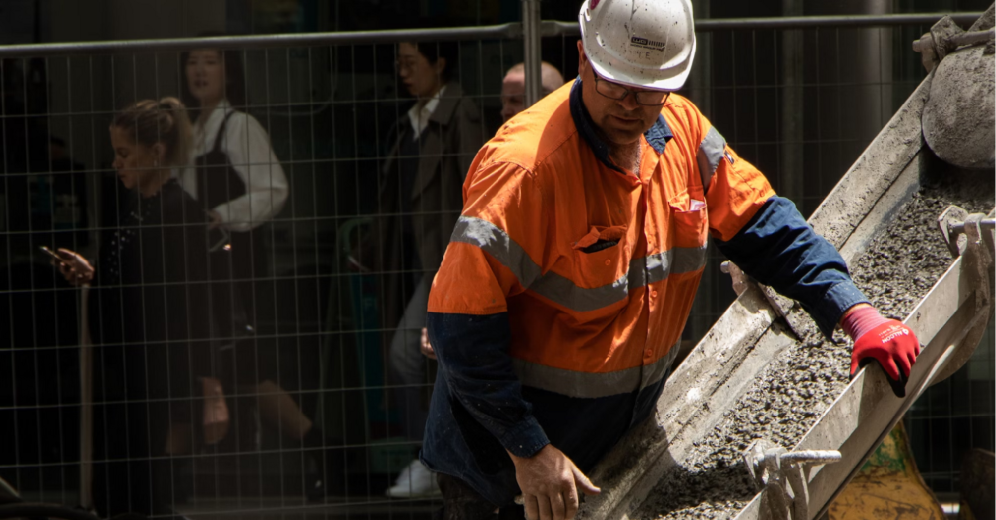 Construction worker pours concrete onto rail tracks