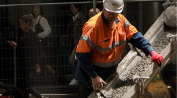 Construction worker pours concrete onto rail tracks