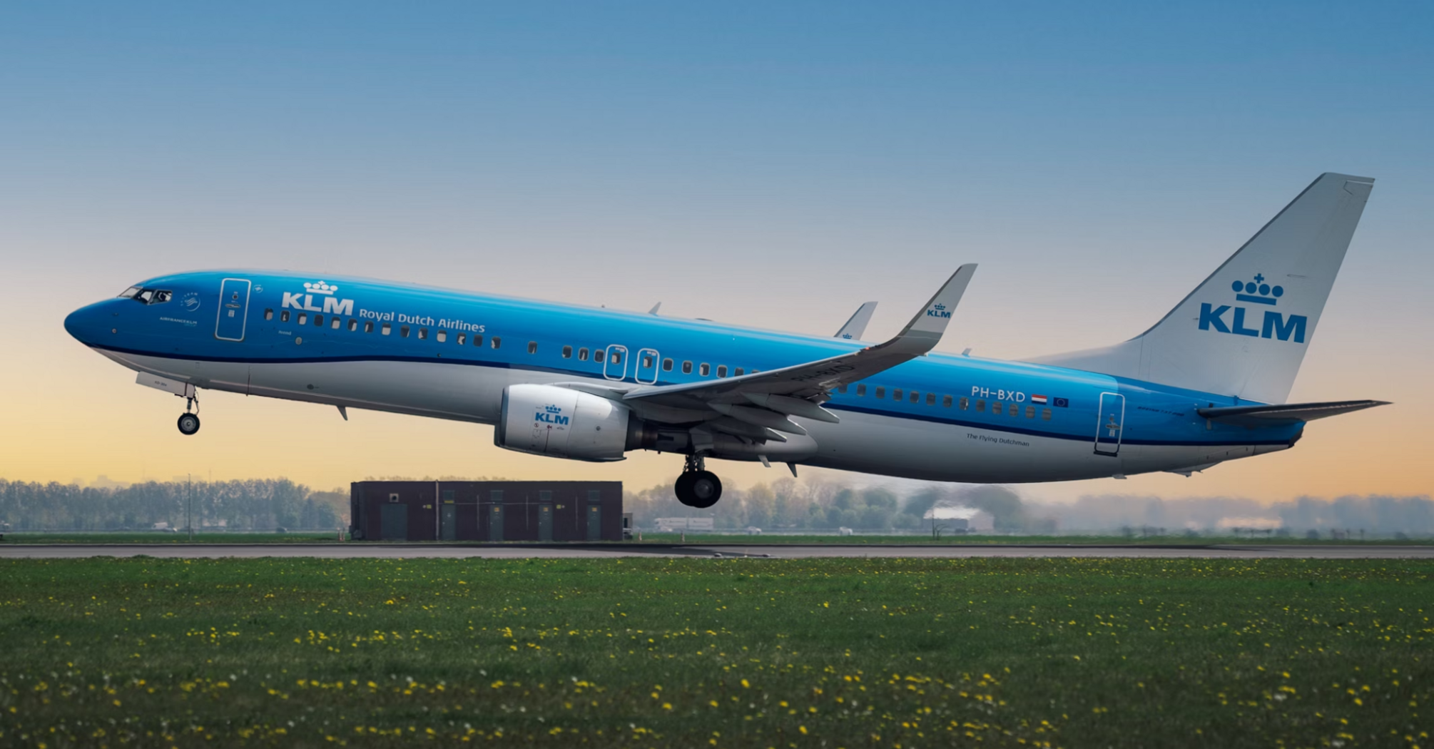 KLM aircraft taking off from runway during sunrise