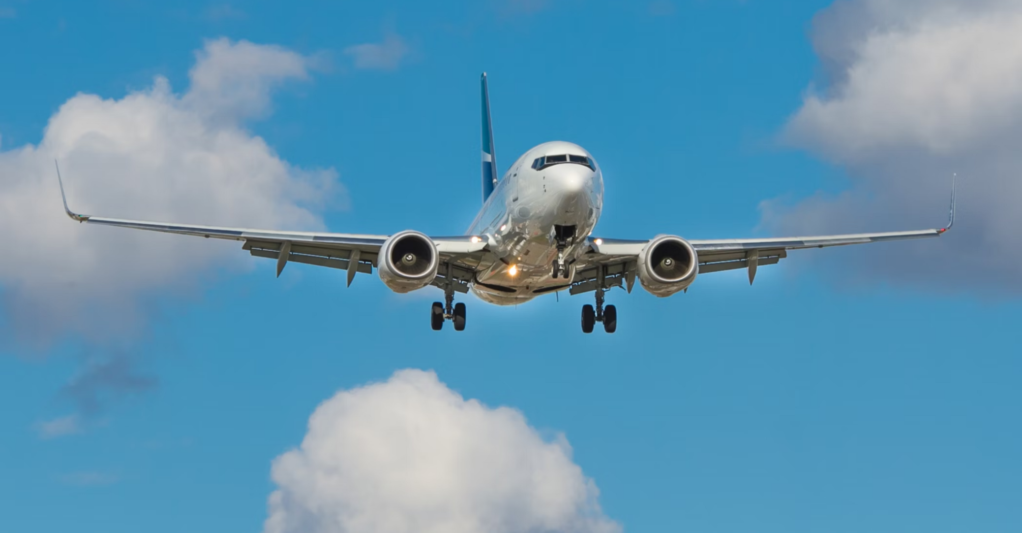 Commercial airplane approaching for landing against blue sky with clouds