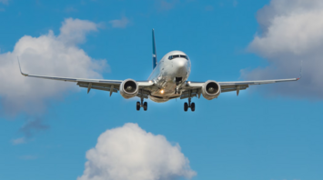 Commercial airplane approaching for landing against blue sky with clouds