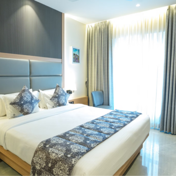 Modern hotel room with large bed, soft lighting, and work desk