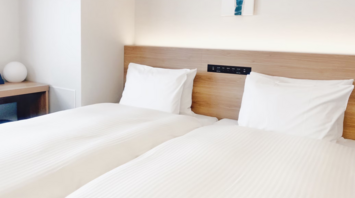 Bright modern hotel room with two neatly made twin beds and minimalist decor