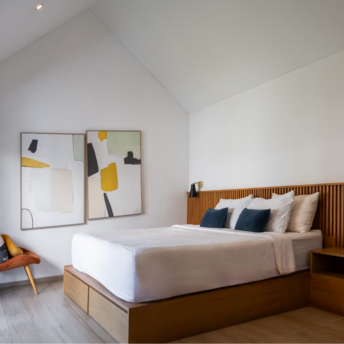 Modern, minimalist hotel bedroom with wooden accents and abstract art