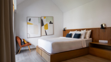 Modern, minimalist hotel bedroom with wooden accents and abstract art