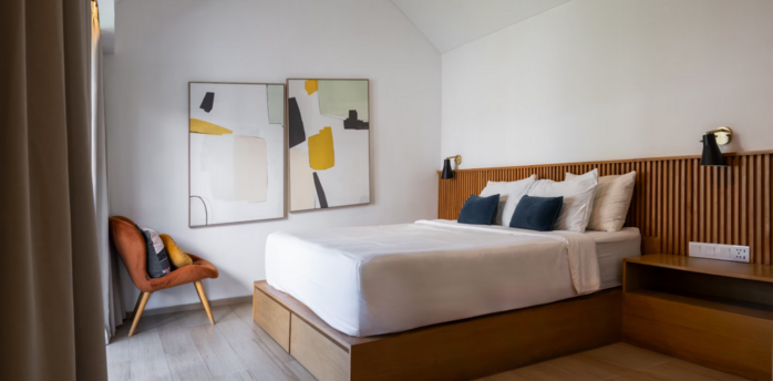 Modern, minimalist hotel bedroom with wooden accents and abstract art