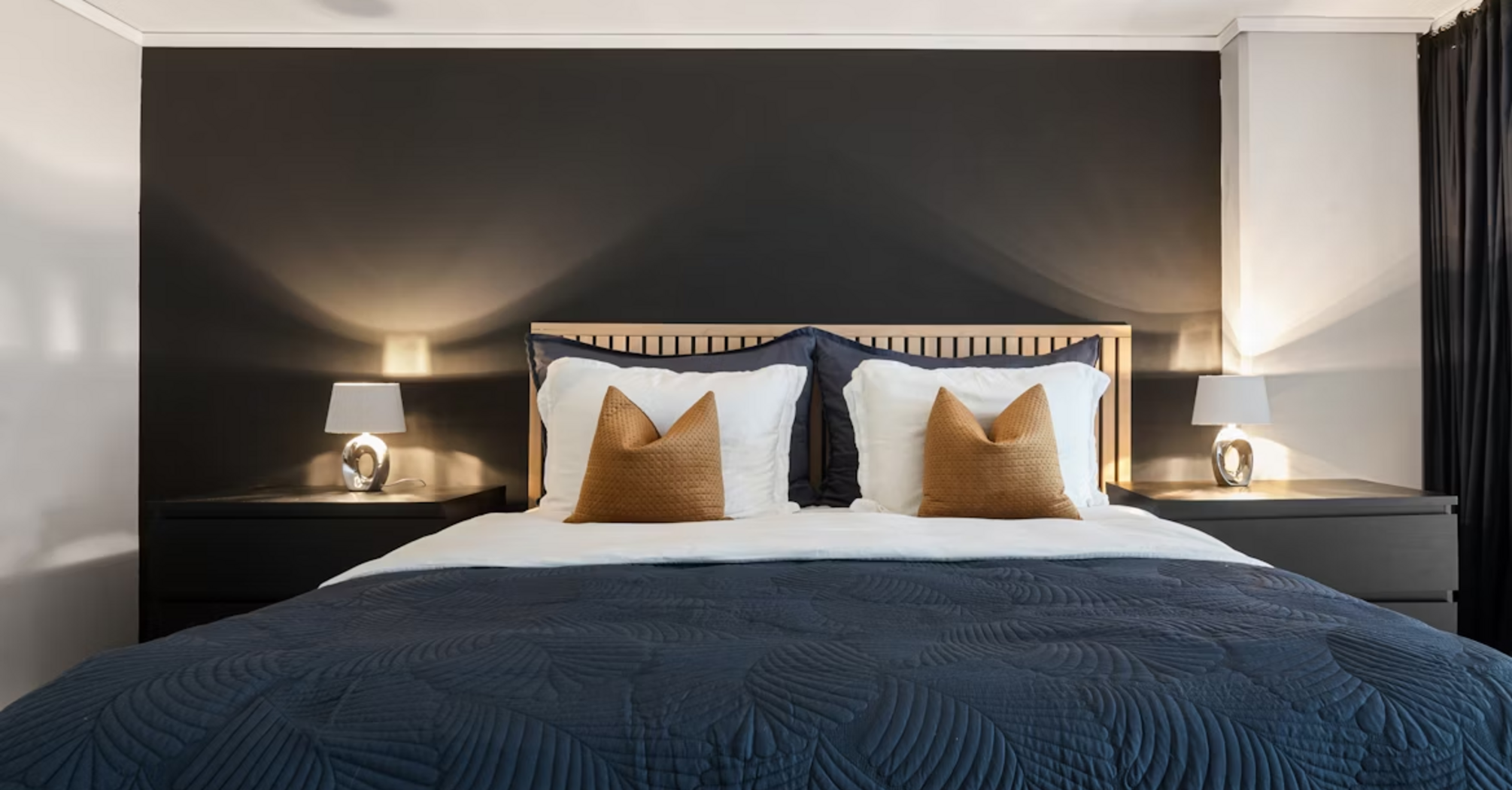 Modern hotel bedroom with dark accent wall and stylish bedding