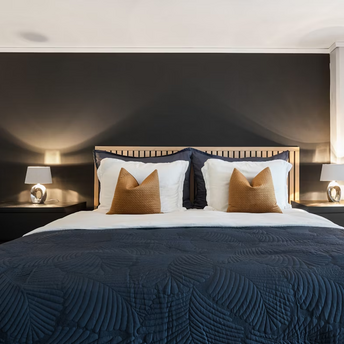 Modern hotel bedroom with dark accent wall and stylish bedding