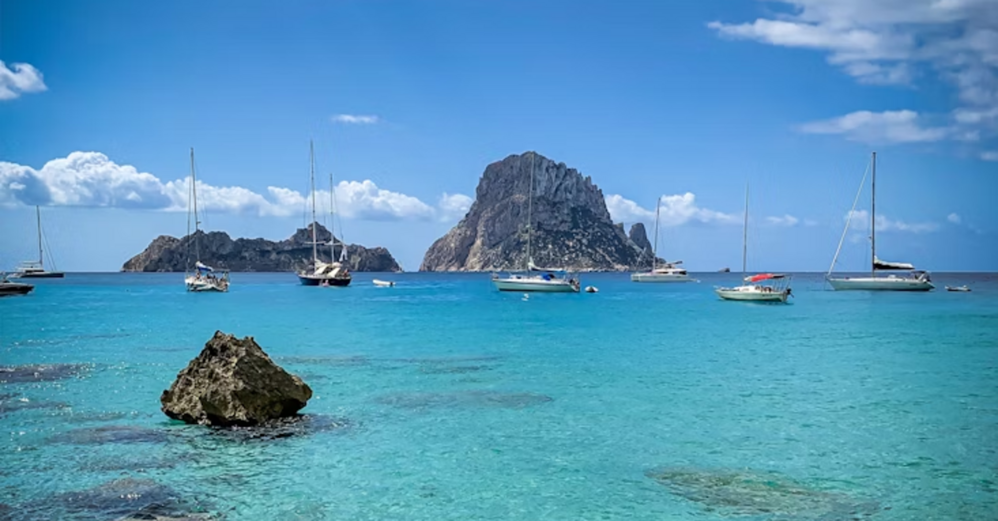 Boats anchored near Es Vedrà rock off the coast of Cala Molí, Ibiza