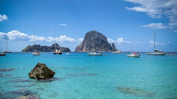 Boats anchored near Es Vedrà rock off the coast of Cala Molí, Ibiza