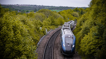 Modern train traveling through green landscape on Calder Valley route