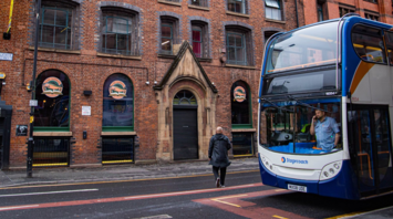 A Stagecoach double-decker bus stops on a city street in front of a historic brick building