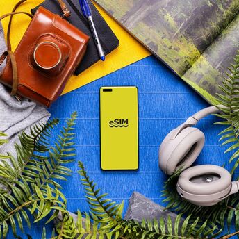 Smartphone with eSIM screen surrounded by travel accessories