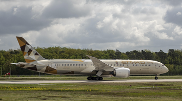 Etihad Airways aircraft taxiing on runway under cloudy sky