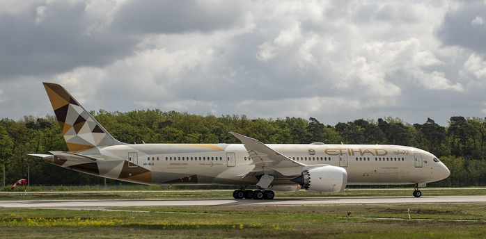 Etihad Airways aircraft taxiing on runway under cloudy sky