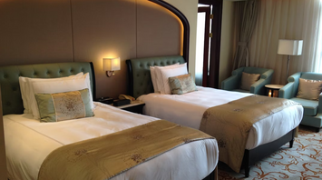 Twin-bed hotel room with elegant decor and armchairs