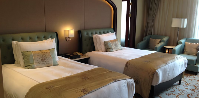 Twin-bed hotel room with elegant decor and armchairs