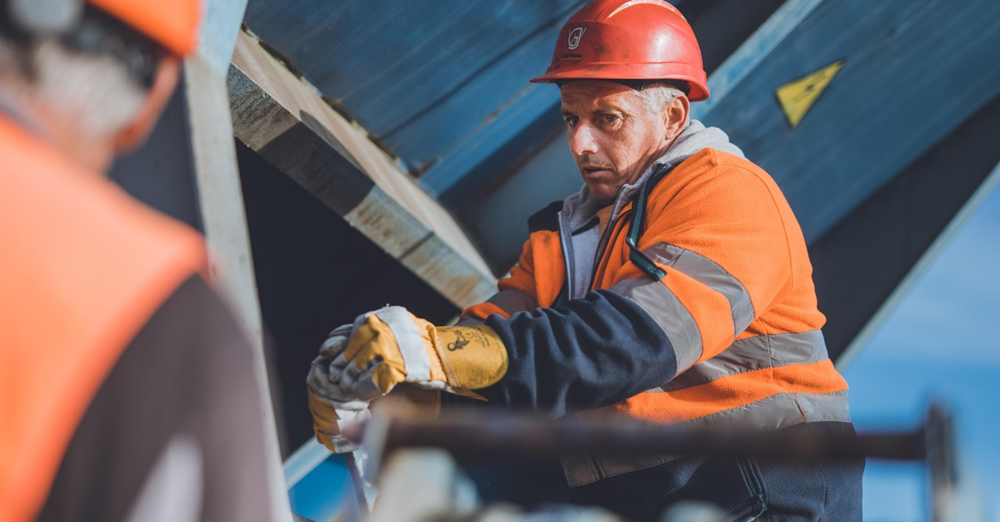 Worker in safety gear at a construction site handling equipment near railway infrastructure
