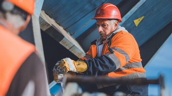 Worker in safety gear at a construction site handling equipment near railway infrastructure