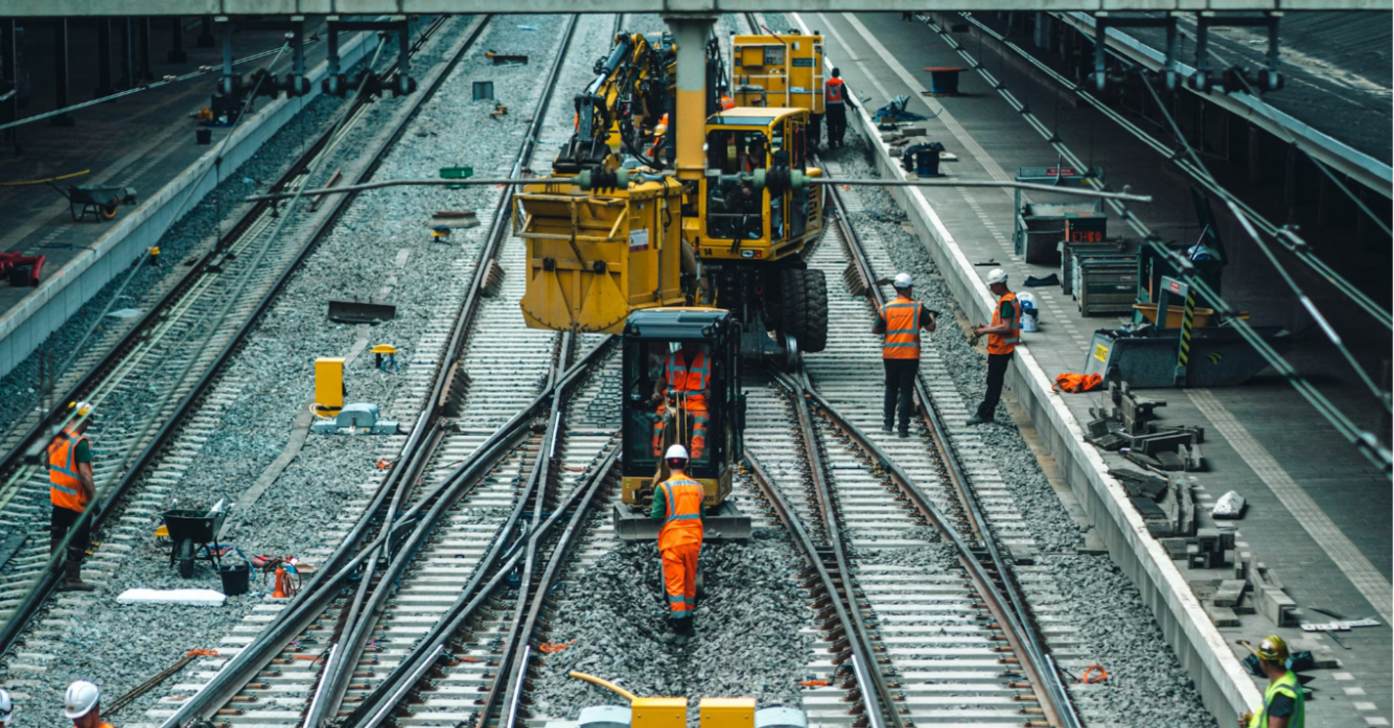 Rail workers performing track upgrades at a busy station