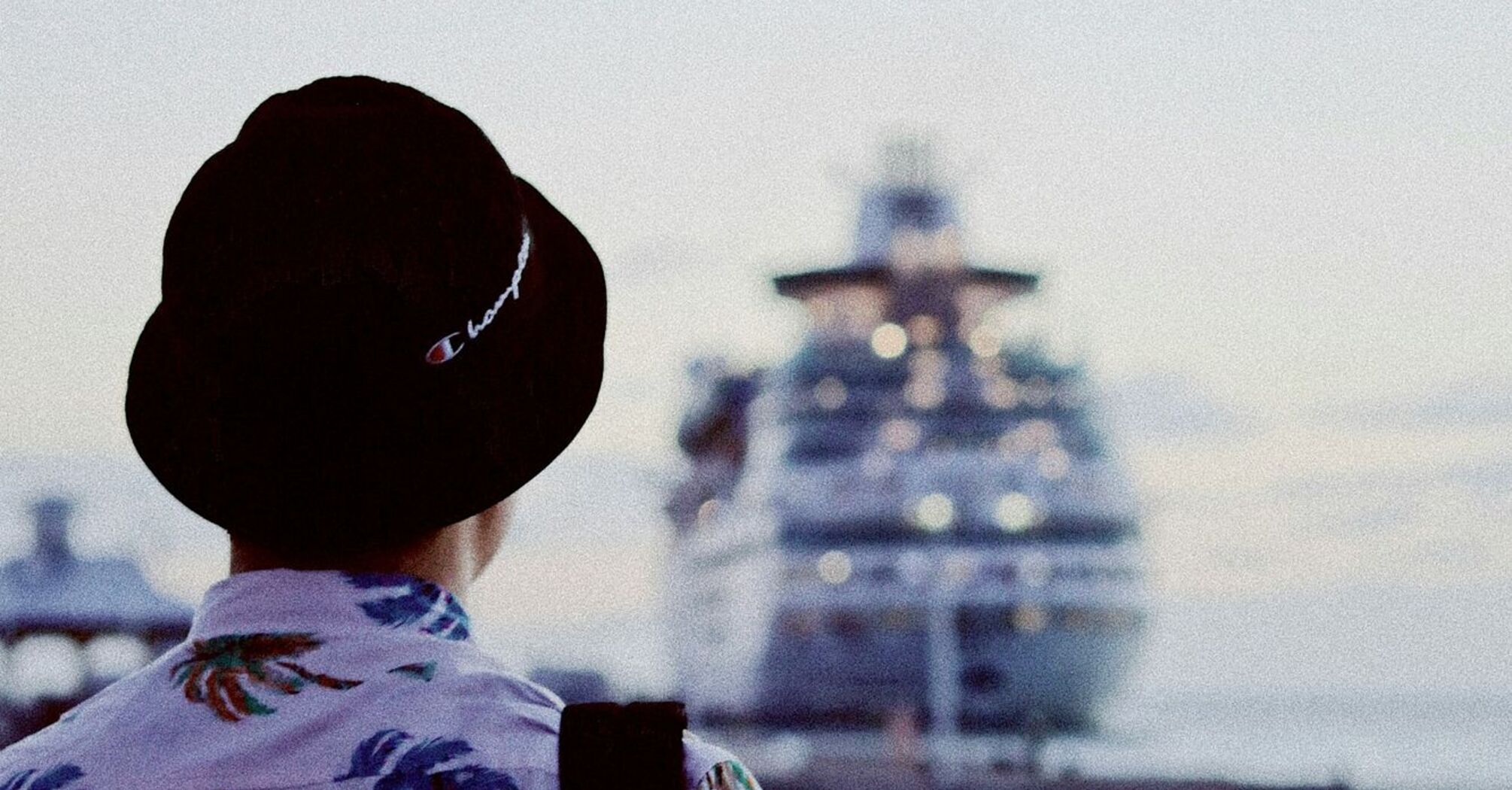 Person in tropical shirt looking at a docked cruise ship