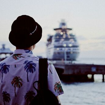 Person in tropical shirt looking at a docked cruise ship