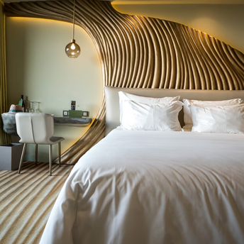 Modern hotel room with white bedding and sculptural wooden wall design