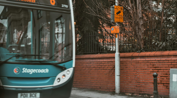 Stagecoach bus on urban street near brick wall and signposts