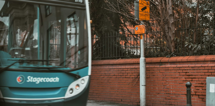 Stagecoach bus on urban street near brick wall and signposts