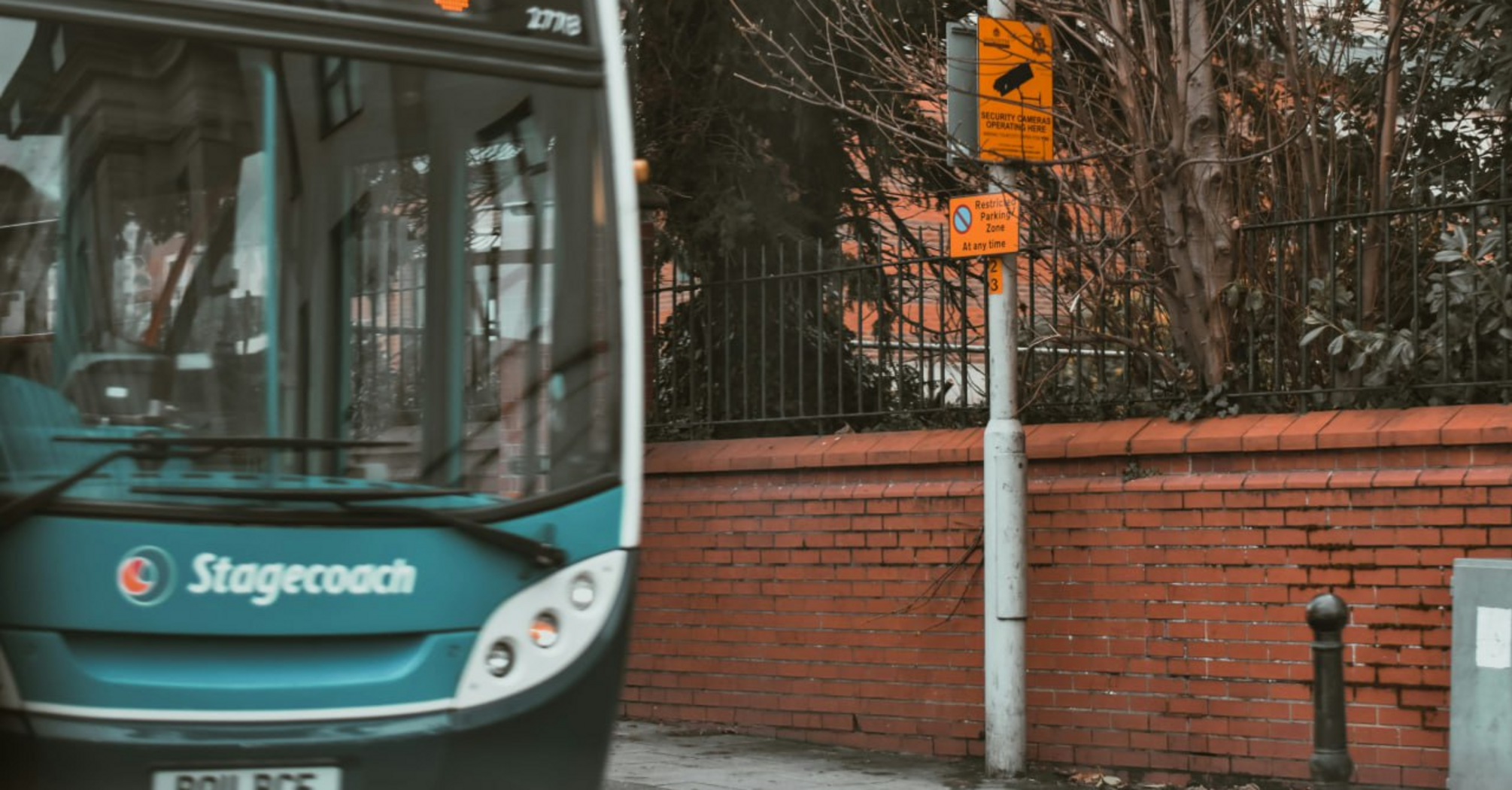 Stagecoach bus on urban street near brick wall and signposts