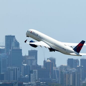 Delta Airbus A350 taking off over city skyline