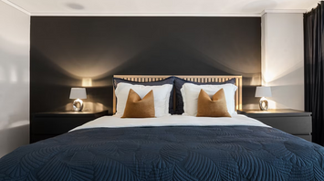 Modern double bed in a stylish hotel room with dark walls and warm lighting